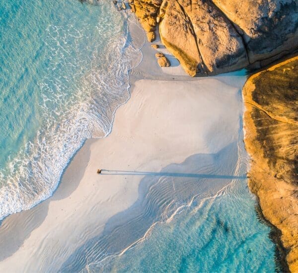 Ariel view of beautiful beach with one person walking and big rocks