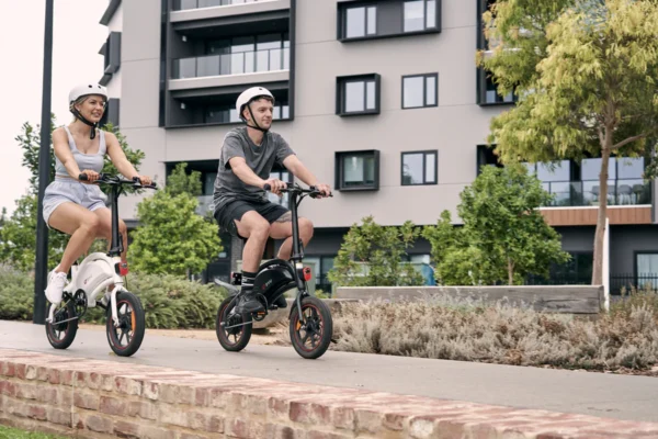 A girl and boy riding electric scooters on a footpath