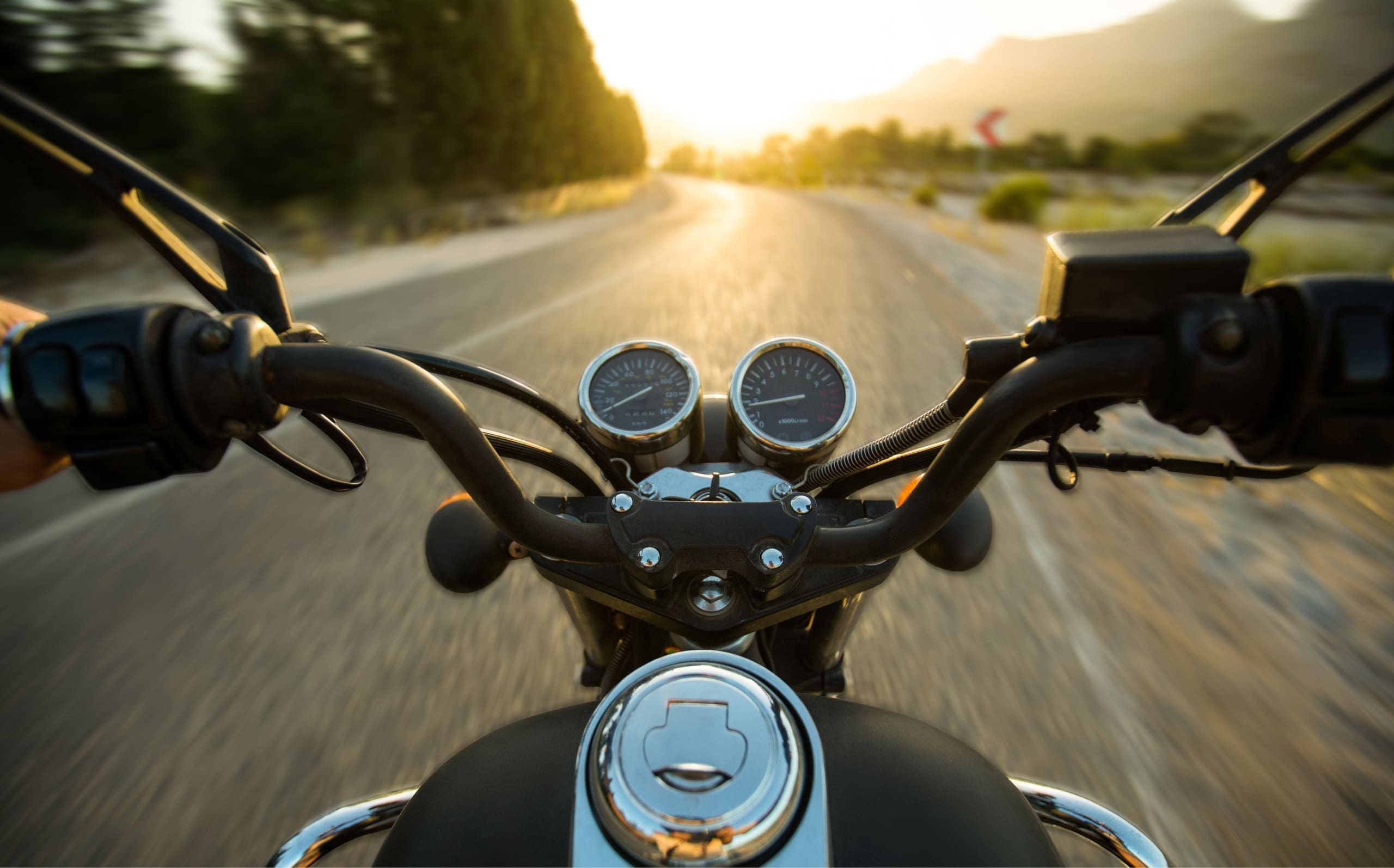 Motorbike handlebars and speedometer on highway at sunrise