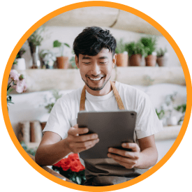 smiling man holding tablet and plants in background@2x
